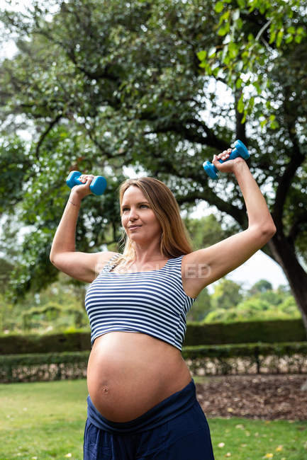 Беременная привлекательная женщина тренируется с гантелями — стоковое фото