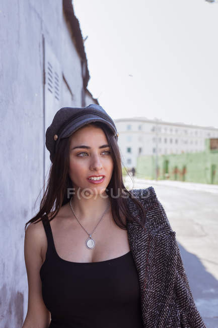 Задумчивая латиноамериканка в кепке, идущая по улице — стоковое фото