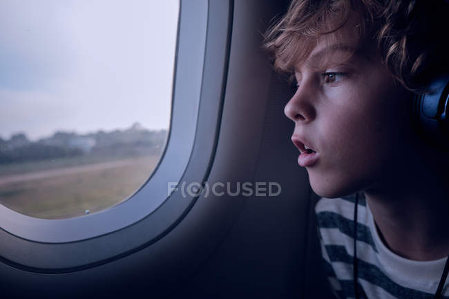Милий хлопчик з навушниками в літаку — стокове фото
