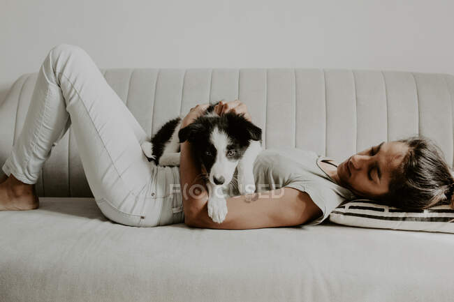 Adolescente avec chiot mignon sur canapé — Photo de stock