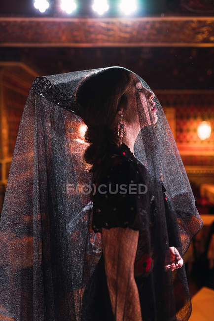 Вид збоку привабливої жінки в фаті і одязі на сцені, освітлені світлом — стокове фото