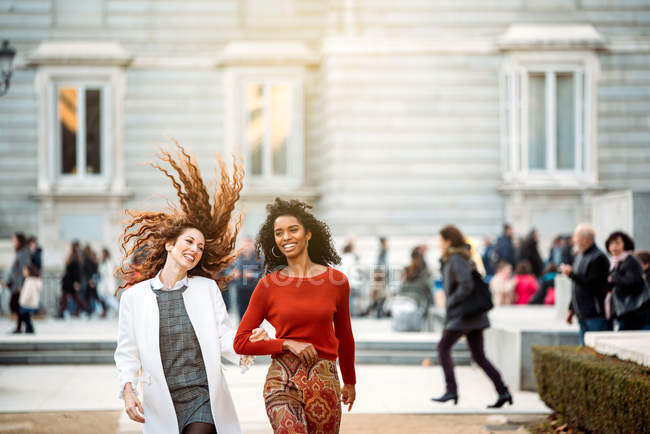 Zwei fröhliche junge Frauen, die im Winter durch die Straßen Madrids gehen — Stockfoto