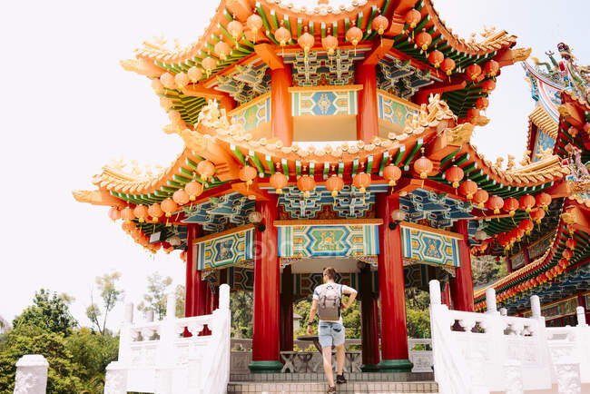 Indietro vista giovane ragazzo con lo zaino salendo in colorato meraviglioso edificio asiatico in Malesia — Foto stock