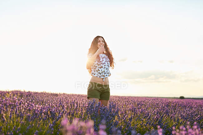 Jovem mulher de pé entre campo de lavanda violeta — Fotografia de Stock