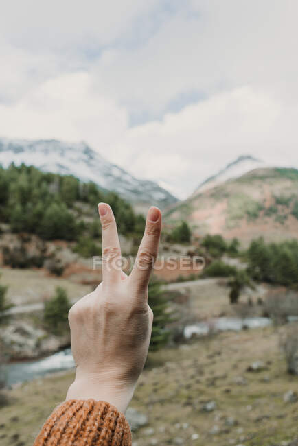 Mãos de colheita de senhora mostrando gesto de vitória e vista pitoresca do vale com montanhas maravilhosas e céu nublado em Pirinéus — Fotografia de Stock