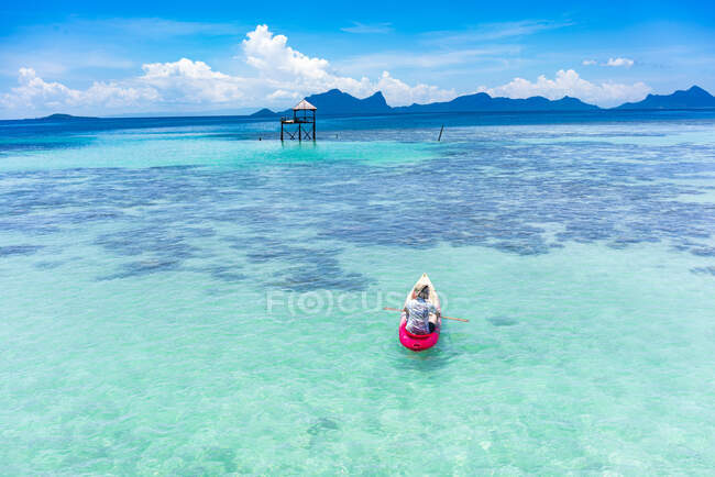 У Малайзії самець катається на каное з веслом на дивовижному блакитному морі і синьому небі. — стокове фото