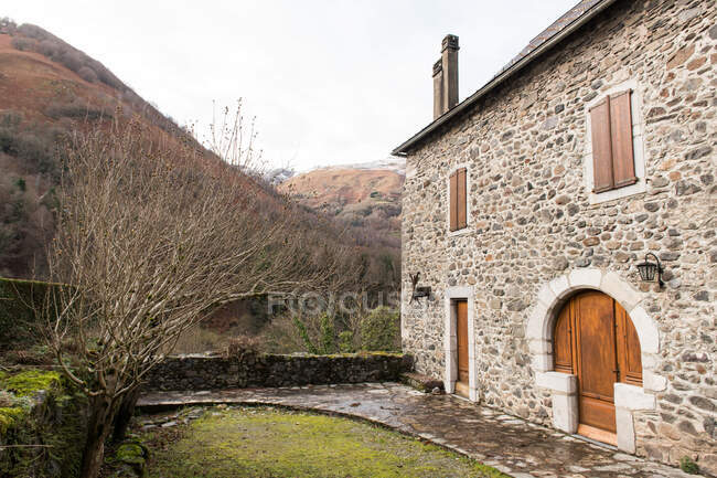 Yard with green grass between grey rock old house with red doors in Pyrenees — Stock Photo