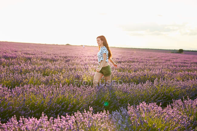 Giovane donna che cammina tra il campo di lavanda viola — Foto stock