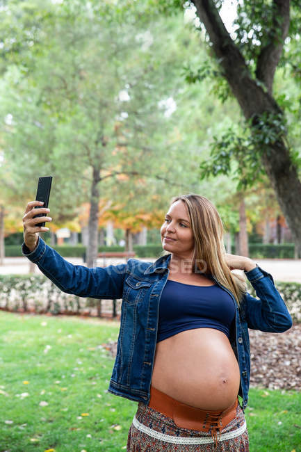 Mulher atraente grávida usando telefone celular — Fotografia de Stock