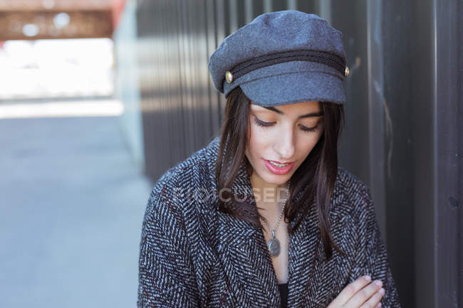 Stylish Hispanic young lady standing near wall and looking down — Stock Photo