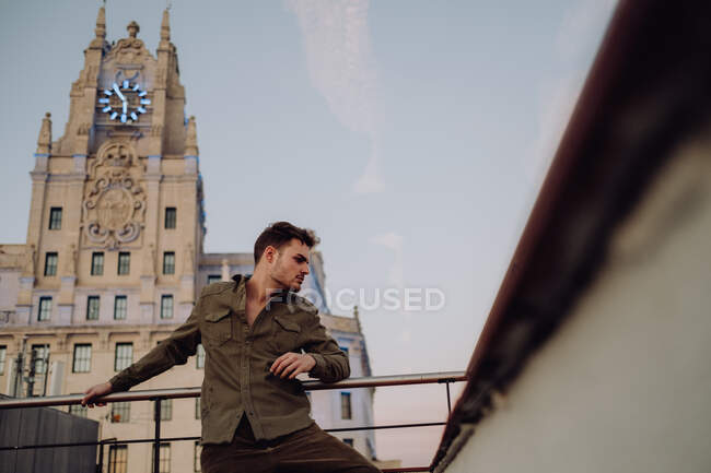Beau homme sur le toit près de vieux bâtiments et énorme bannière — Photo de stock