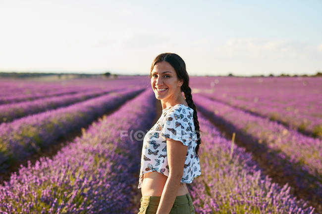 Jovem mulher de pé entre campo de lavanda violeta — Fotografia de Stock