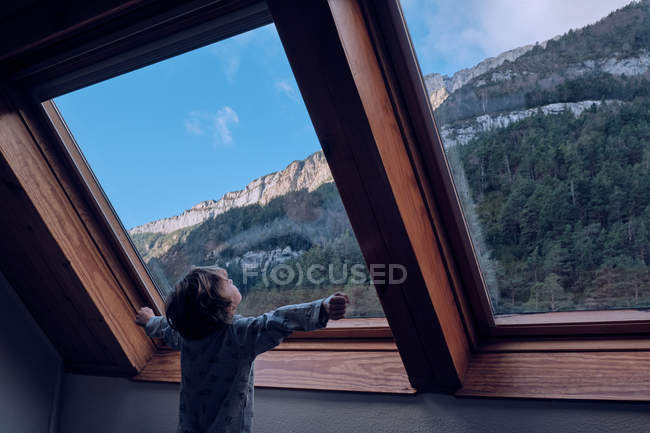 Мальчик смотрит на гору через окно — стоковое фото
