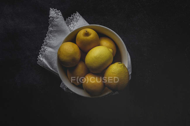 Limoni freschi in ciotola bianca su fondo scuro — Foto stock