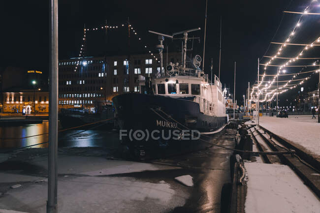 Сучасний корабель стоїть біля пірса в крижаному порту яскраво освітленого арктичного міста вночі. — стокове фото