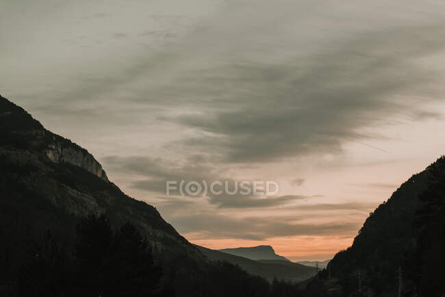 Pintoresca vista de las altas montañas con árboles durante la puesta del sol en los Pirineos - foto de stock