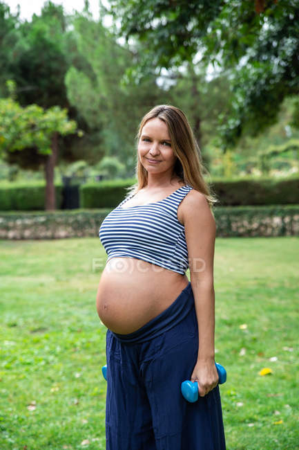 Беременная привлекательная женщина тренируется с гантелями — стоковое фото