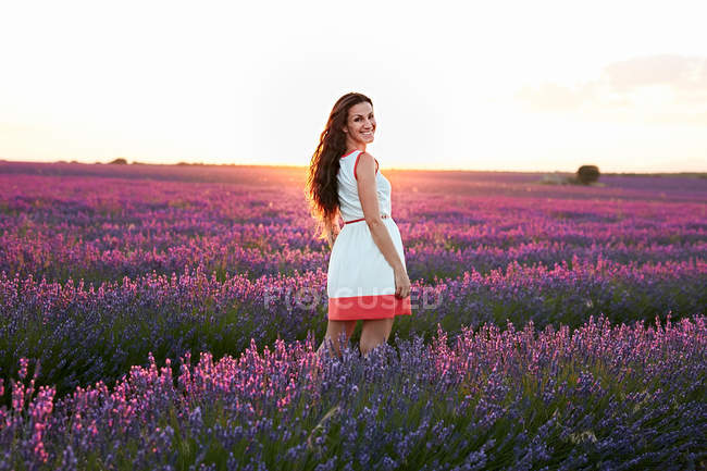 Jeune femme debout entre champ de lavande violette — Photo de stock