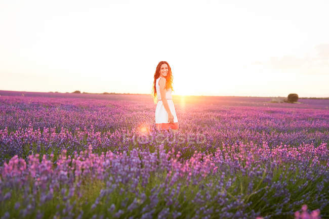 Sorrindo jovem mulher entre campo de lavanda violeta — Fotografia de Stock