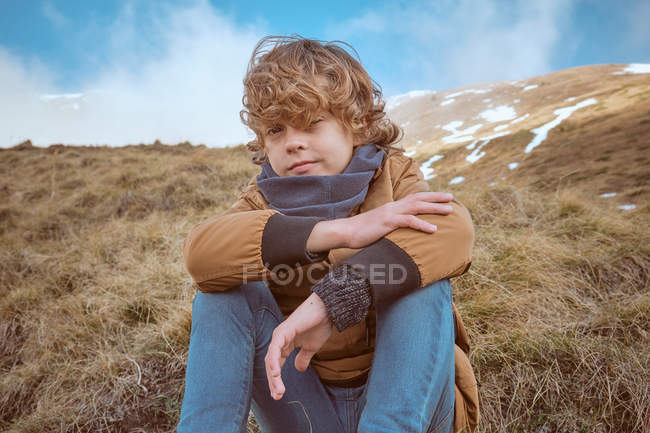 Симпатичний хлопчик сидить на пагорбі біля струмка — стокове фото