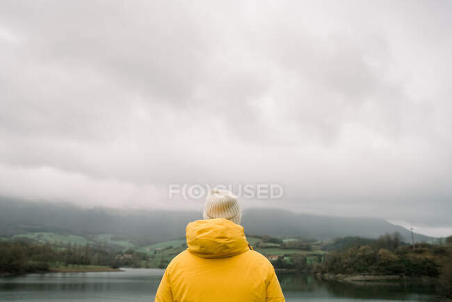 Person im Mantel mit Kamera in der Nähe des Sees — Stockfoto