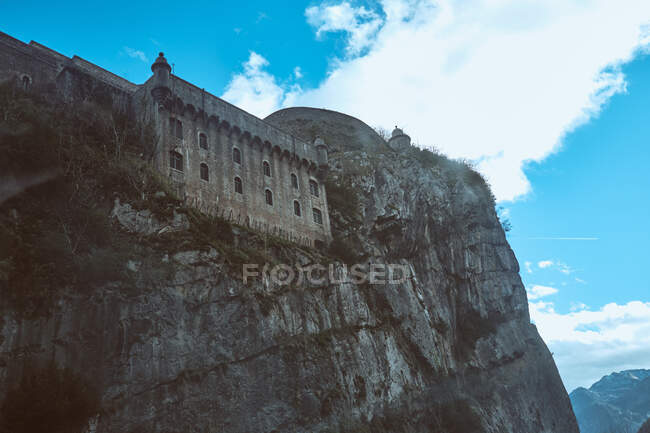 Древний замок, стоящий на краю каменистой скалы на фоне облачного голубого неба в Уэске, Испания — стоковое фото
