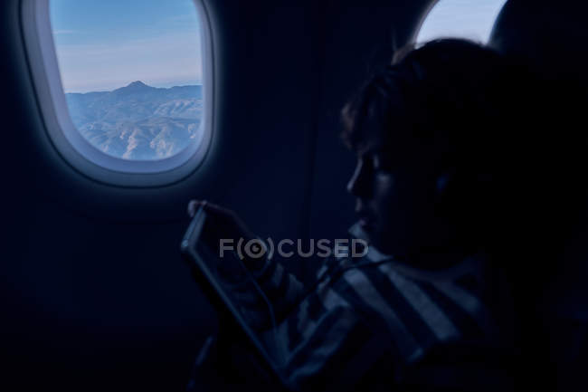 Bonito menino assistindo filme no tablet no avião — Fotografia de Stock