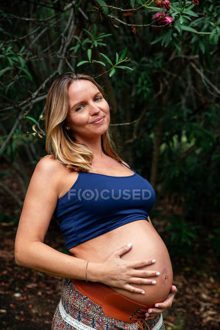 Sonriendo embarazada atractiva mujer en el parque - foto de stock