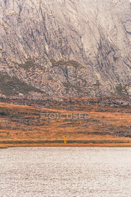 Person in gelbem Regenmantel am Ufer des Sees in der Nähe eines Berges in Isoba, Kastilien und León, Spanien — Stockfoto