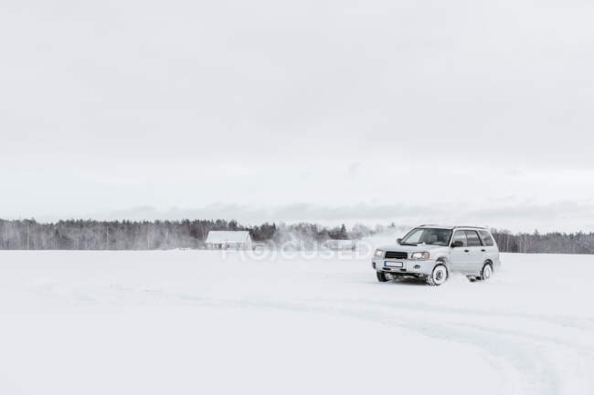 Carro dirigindo no campo de neve — Fotografia de Stock