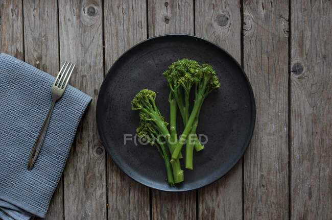 De arriba tiro de tenedor y servilleta acostado cerca del plato con brócoli verde saludable - foto de stock