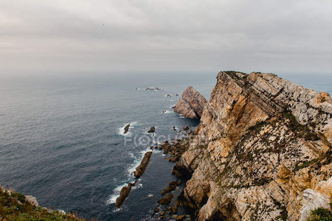 Magnifique vue sur la falaise rocheuse rugueuse près de la mer étonnante par jour gris au Cap des Pois, Asturies — Photo de stock