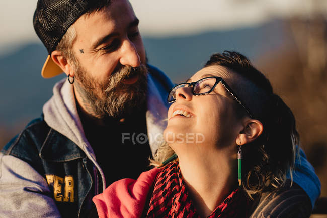 Bärtiger Mann umarmt fröhliche Frau in Waldnähe auf verschwommenem Hintergrund — Stockfoto