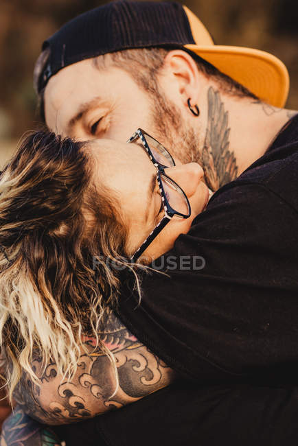 Homem barbudo abraçando mulher alegre perto de madeira na floresta no fundo borrado — Fotografia de Stock