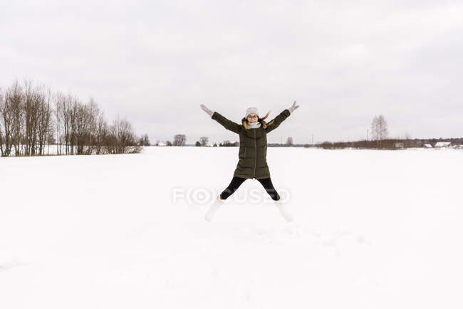 Jovencita en invierno se divierte en prado de nieve y cielo nublado en Vilna, Lituania - foto de stock