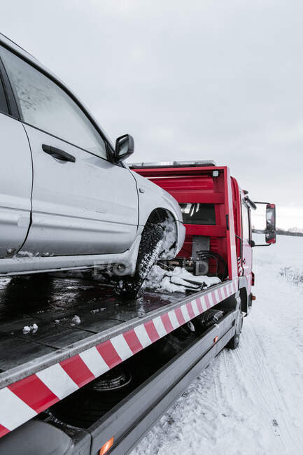 Broken automobile on breakdown truck on snow meadow in Vilnius, Lithuania — Stock Photo