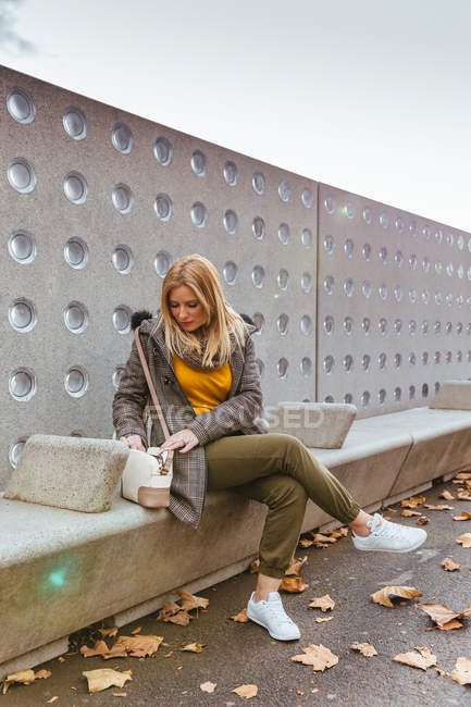 Portrait of blond girl looking in her bag — Stock Photo