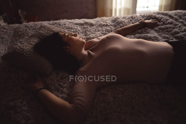 Giovane donna sdraiata sul letto — Foto stock