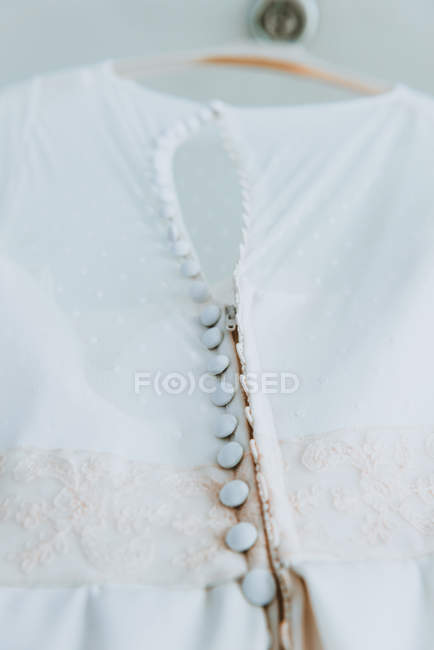 Nahaufnahme-Knöpfe an elegantem weißen Hochzeitskleid auf Kleiderbügel — Stockfoto
