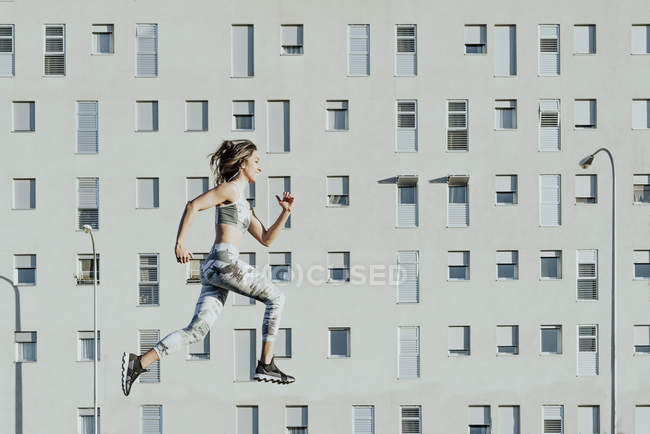 Frau in Sportbekleidung springt nahe Gebäude — Stockfoto