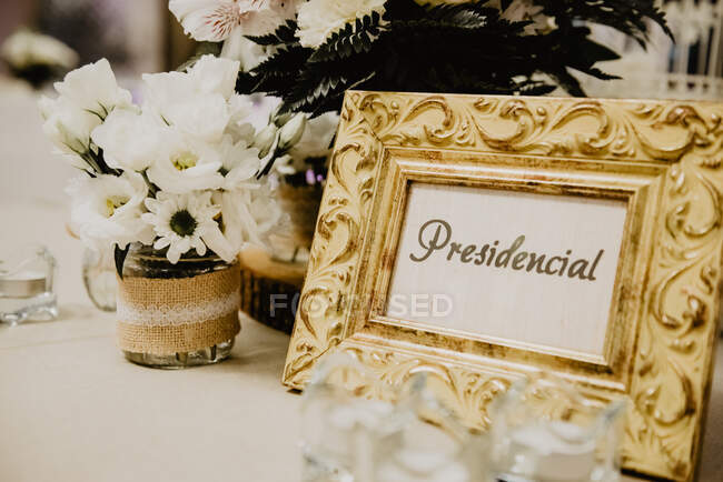 Beautiful photo frame near bunch of white blooms in can on table — Stock Photo