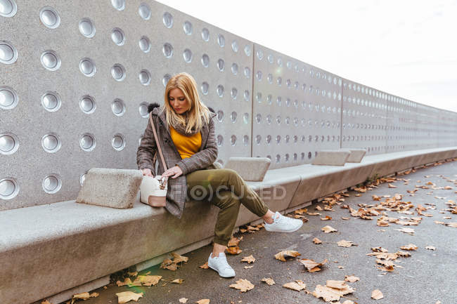 Porträt eines blonden Mädchens, das in ihre Tasche schaut — Stockfoto