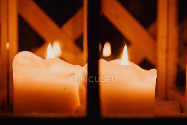 Closeup flaming candles placed in candelabrum between obscurity — Stock Photo