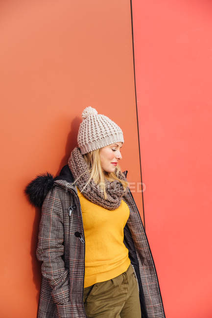 Chica rubia apoyada en una pared colorida - foto de stock