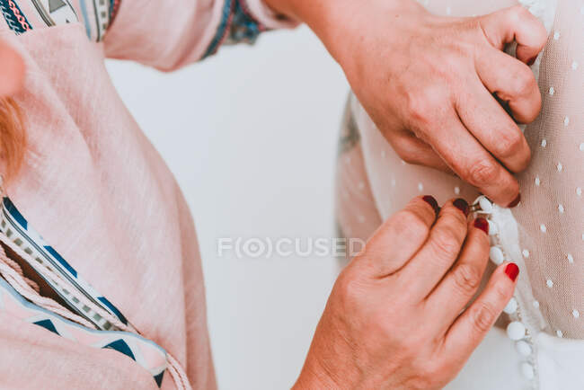Mulher abotoando o vestido de noiva na senhora — Fotografia de Stock