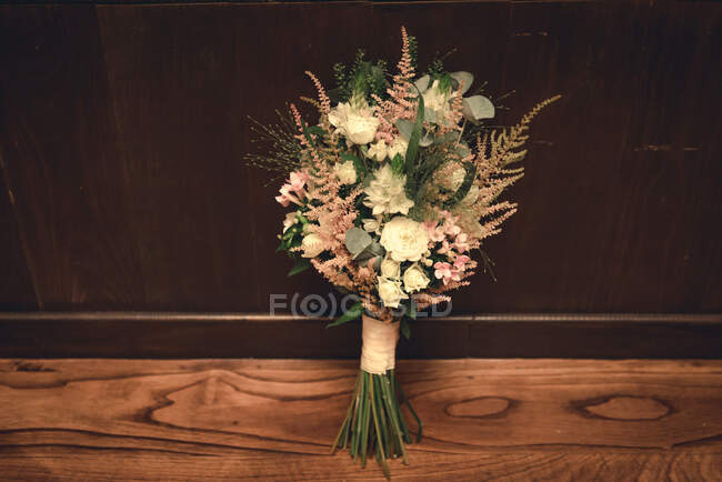 Ramo de hermosas flores aromáticas frescas colocadas en el suelo de madera cerca de la pared - foto de stock