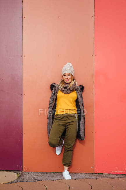 Blonde girl leaning on a colorful wall — Stock Photo