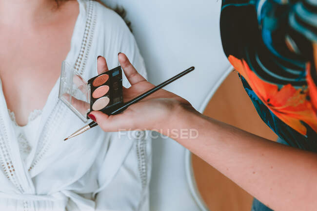 Frauenhand mit Pinsel und Puder in der Nähe der Dame — Stockfoto