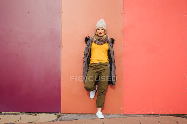 Chica rubia apoyada en una pared colorida - foto de stock