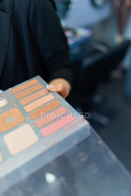 Crop hand of lady holding palette of colourful powder in hairdressing salon — Stock Photo